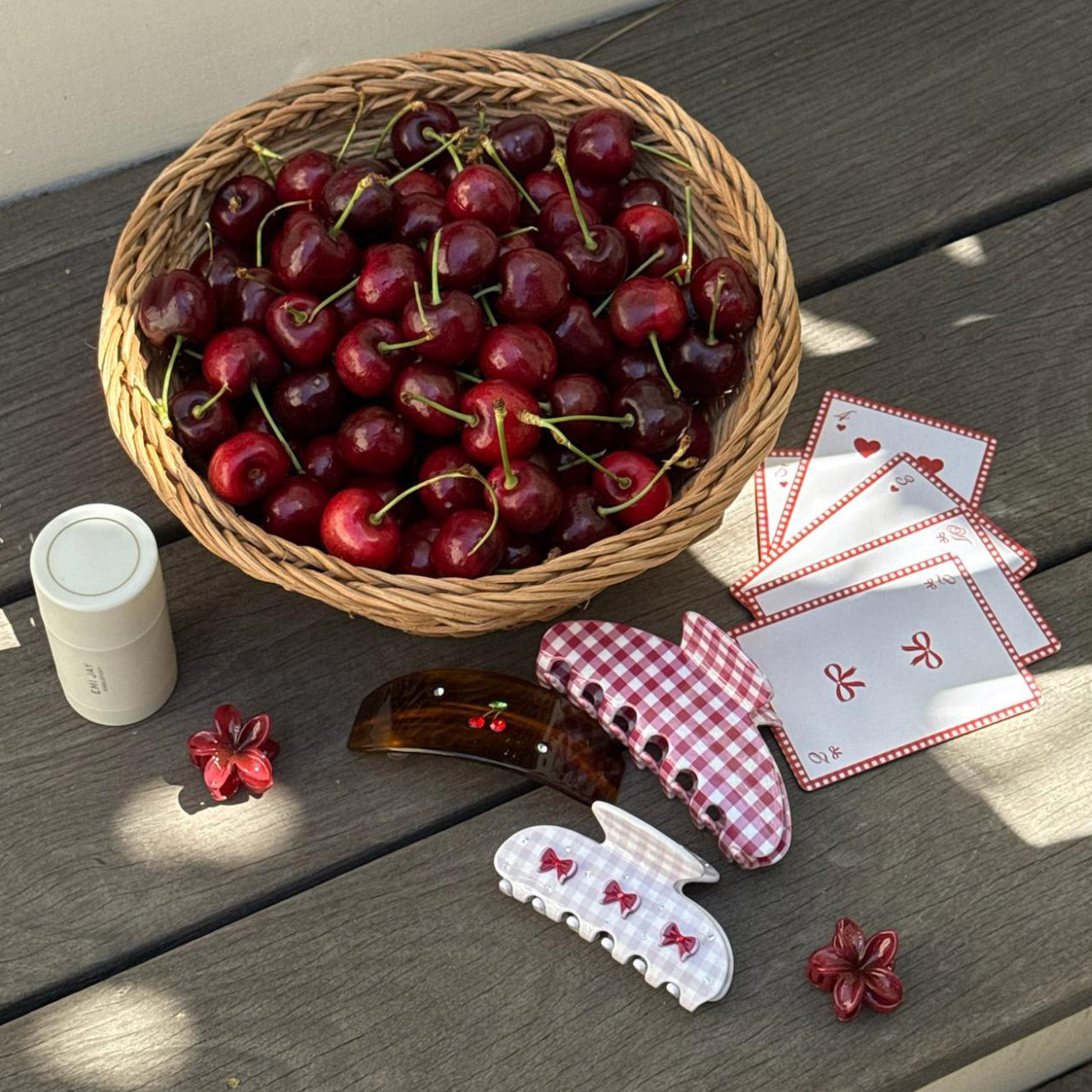 assorted emi jay hair accessories and angelstick next to a basket of cherries and playing cards