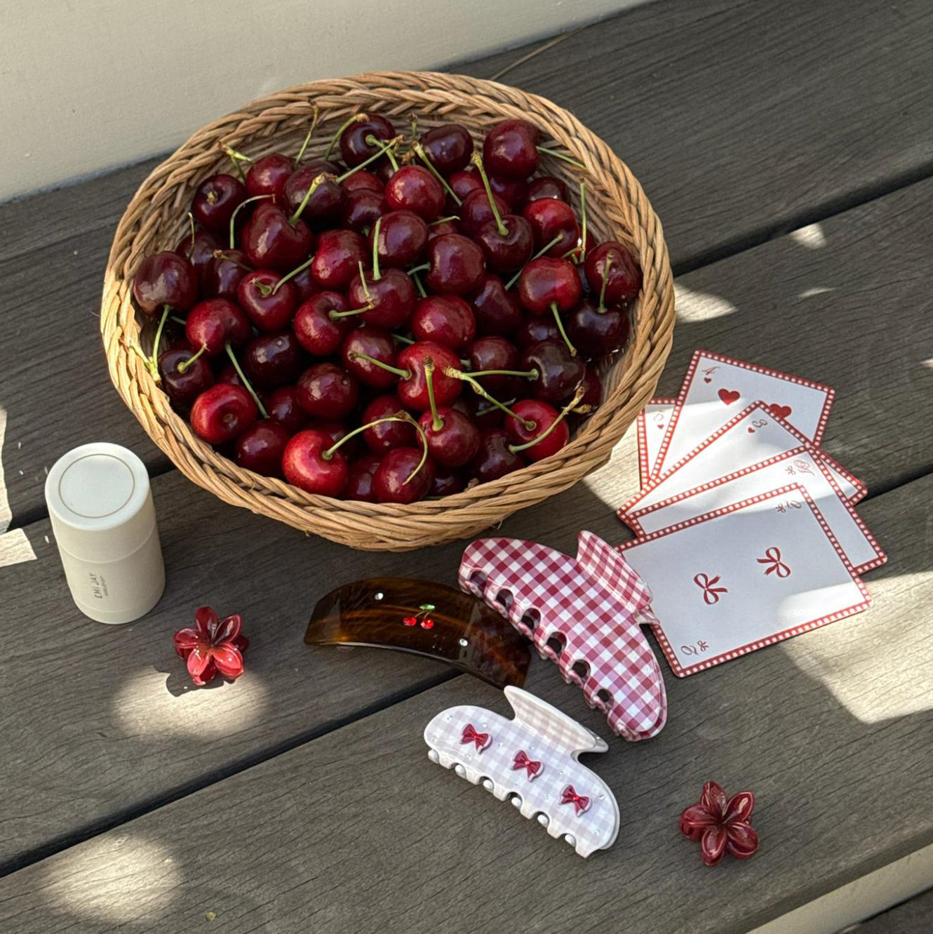 assorted hair claw clips, hair care, playing cards, and cherries in a basket.