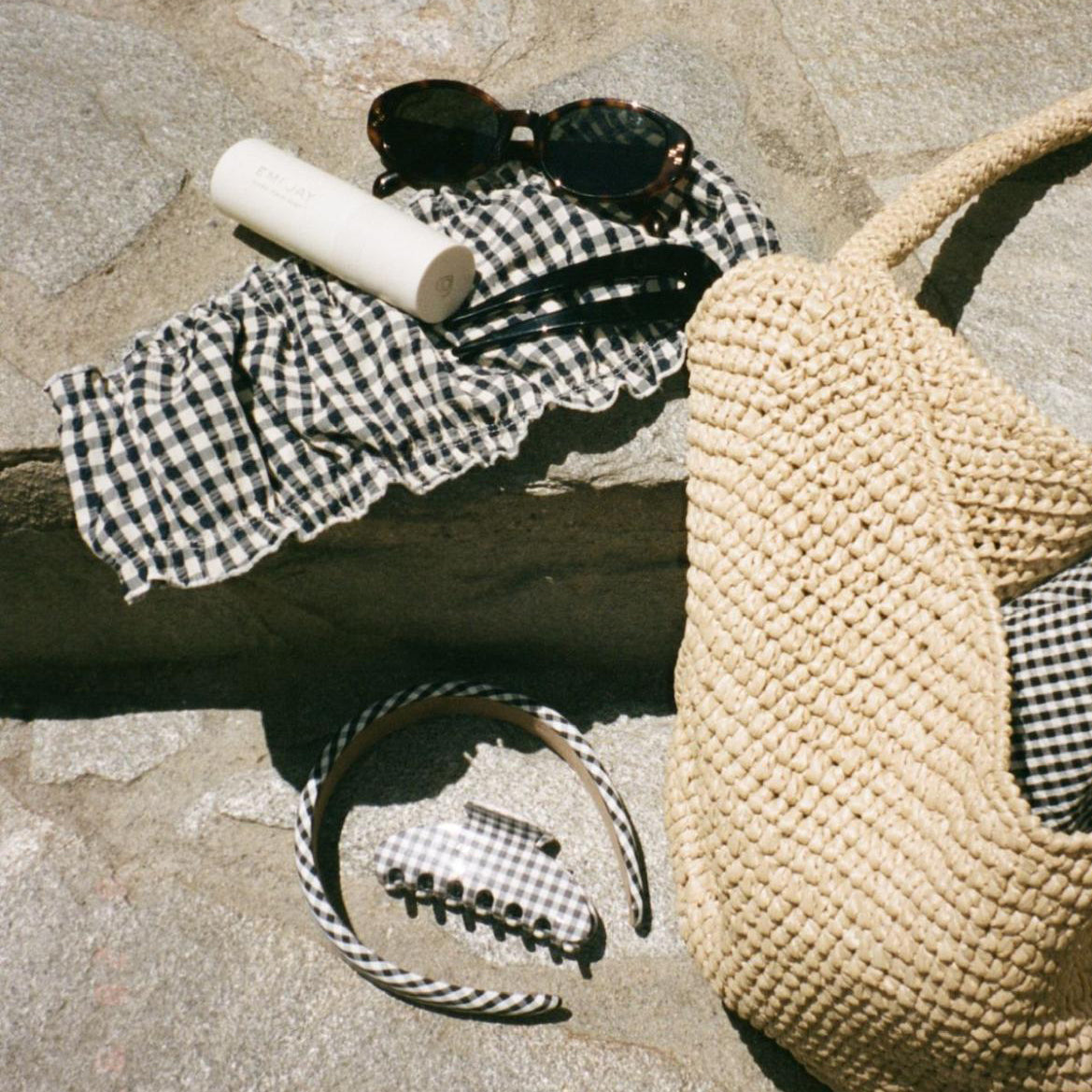 assorted hair care and accessories with a purse and sunglasses on stone steps
