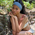 model sitting next to rocks with chin on hands and Infinity Headband in Navy Gingham in hair