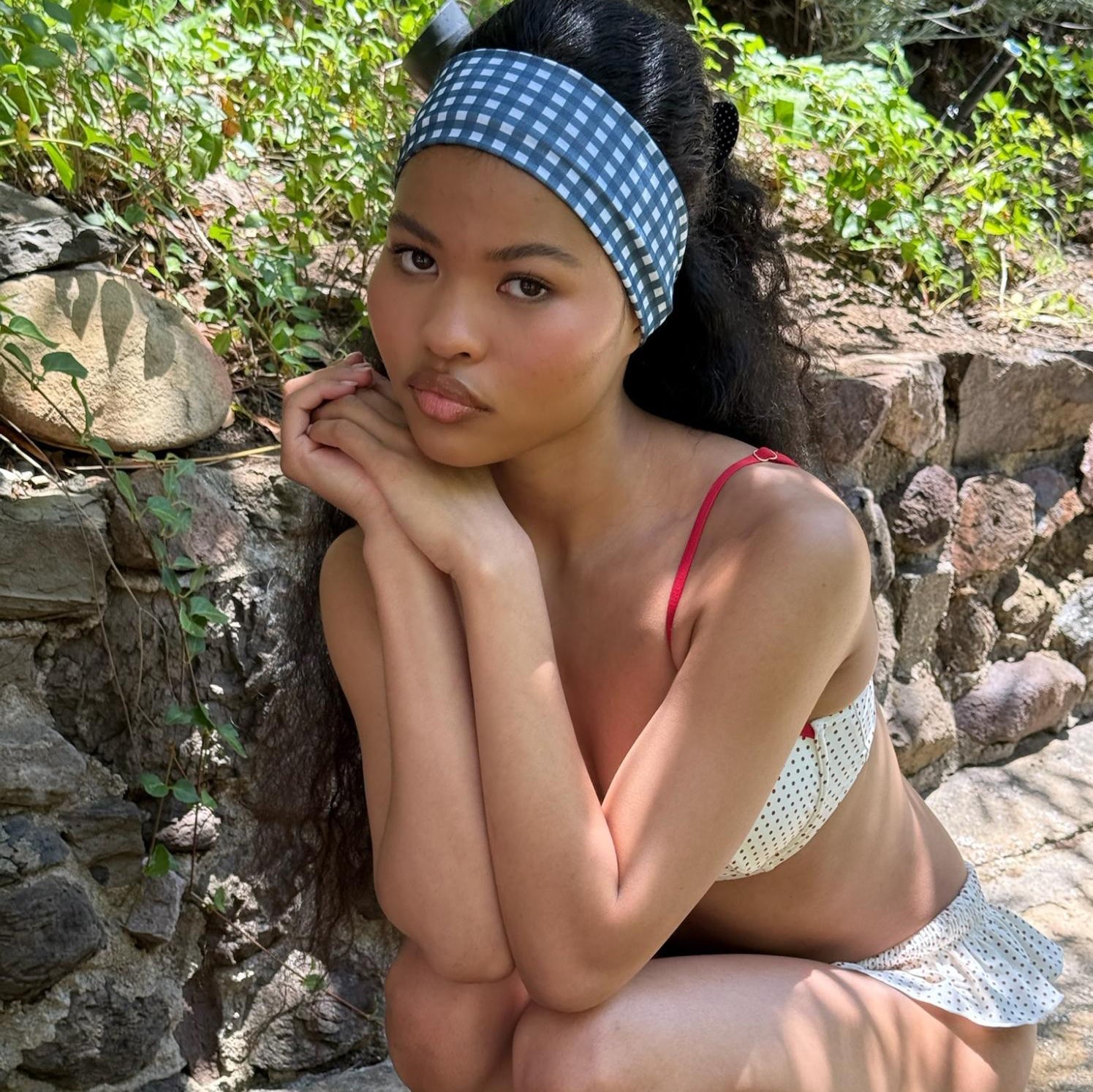 model sitting next to rocks with chin on hands and Infinity Headband in Navy Gingham in hair