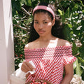 model holding cherry while standing with Halo Headband in Cherry Gingham in hair