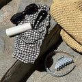 assorted hair care and accessories on stone steps with bag and sunglasses