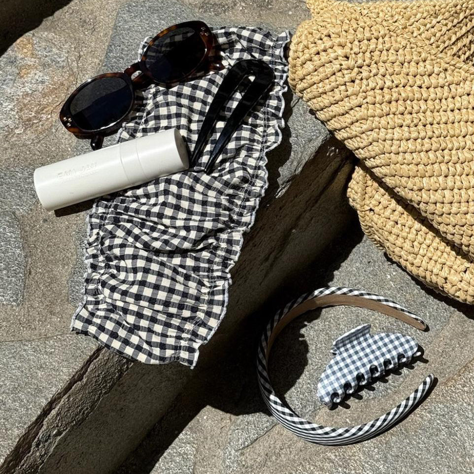 assorted hair care and accessories on stone steps with bag and sunglasses