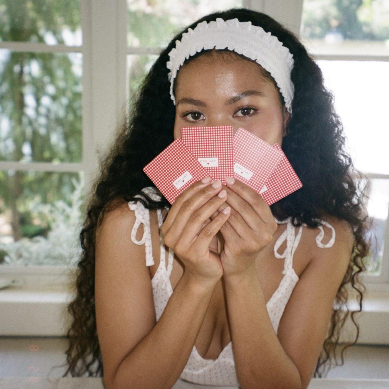 model holding playing cards in front of face while wearing Ruffle Headband in Daffodil in hair